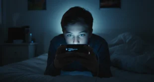Joven adolescente mirando el celular en la oscuridad de su habitación