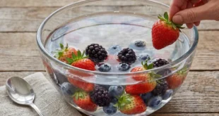 Tazón de fresas y arándanos sumergidos en agua con bicarbonato para eliminar residuos de pesticidas de su superficie