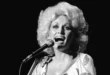 Dolly Parton sonriendo con su icónica melena rubia en un escenario