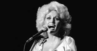 Dolly Parton sonriendo con su icónica melena rubia en un escenario