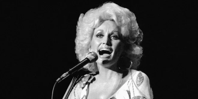 Dolly Parton sonriendo con su icónica melena rubia en un escenario