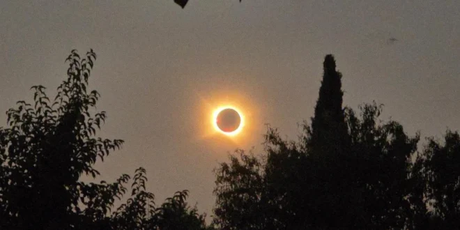 La corona solar brillando intensamente detrás de la silueta negra de la Luna durante el eclipse total