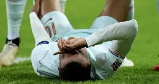 Kylian Mbappé lamentándose sobre el césped tras sufrir una lesión de rodilla con la selección francesa.
