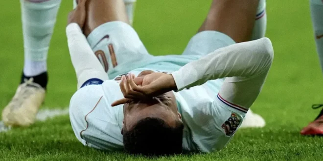 Kylian Mbappé lamentándose sobre el césped tras sufrir una lesión de rodilla con la selección francesa.