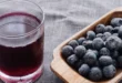 Vaso de jugo de arándano puro y bayas frescas sobre una mesa para evaluar su efecto en los dientes