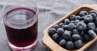 Vaso de jugo de arándano puro y bayas frescas sobre una mesa para evaluar su efecto en los dientes
